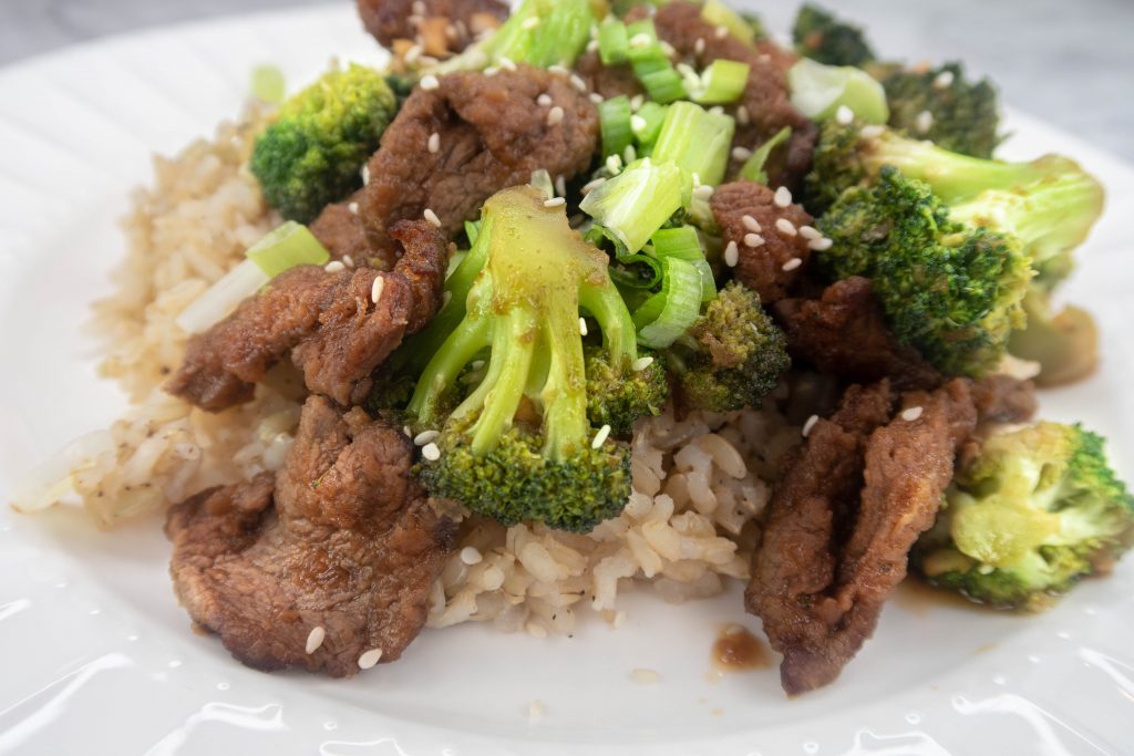 Broccoli and Beef served over brown rice on a plate